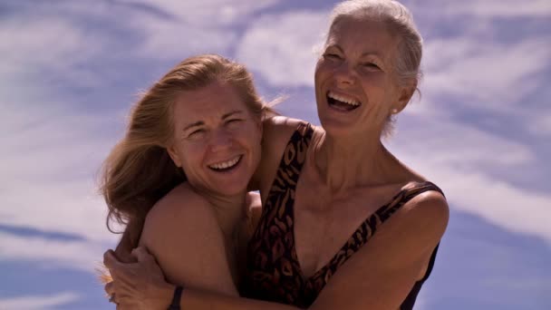 Cinemagraph of a mother and daughter posing for a portrait on the beach with swirling clouds.