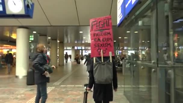 一名积极分子带着写着 与法西斯主义 种族主义和性别歧视作斗争 的红色标语走过火车站 — 图库视频影像