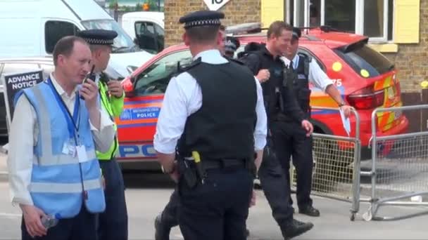 英国7月2017 テロ対策ユニットの2人の武装警察官が青いバンに向かって警官を過ぎて歩く — ストック動画