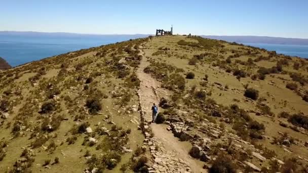 ティティカカ湖の近くのアイラ ソルの山で男がハイキングした後 ボリビアのアンデス山脈で撮影された空中追跡ドローン — ストック動画