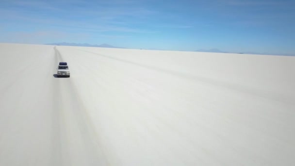 航空追跡ドローンは 車の前で 白いサラー 塩砂漠 ウユニ塩フラット ボリビア 南アメリカで飛んでショット — ストック動画
