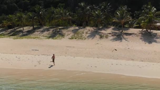 Aerial Slow Motion Drone Shot Man Jogging Beach Clear Turquoise — Vídeo de stock