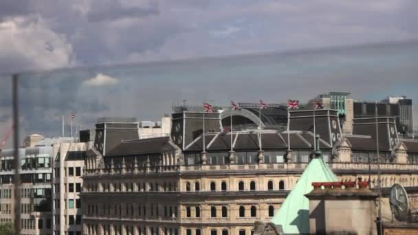 Vlajky Union Jack vlály ve větru nad budovou. Trafalgar Square day time sunny.