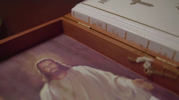 多利穿过装有一本白色圣经和耶稣基督的照片的敞开的木箱 — 图库视频影像