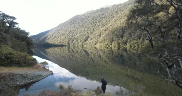 Fille Marchant Vers Lac Calme Avec Reflet Des Montagnes Verdoyantes — Video
