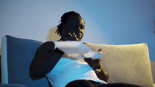 Affrican Man Har Middag Packad Mat Soffa Och Byta Kanaler — Stockvideo
