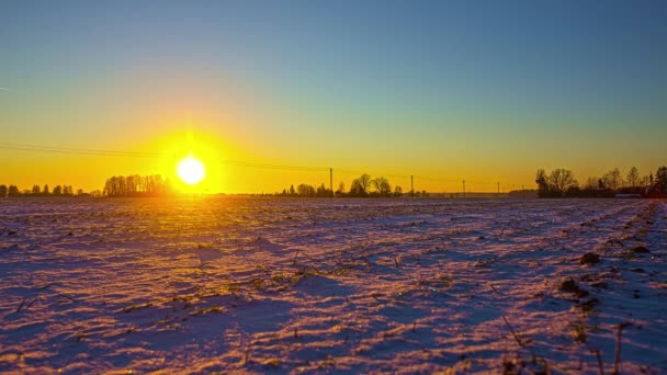 雪に覆われた農民のフィールド冬の空中ドローン映像日没のタイムラプスと 地平線に太陽を沈める — ストック動画