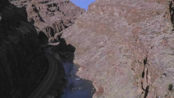 底に川と道路がある砂漠の高い峡谷の劇的な空中 ドローンショット — ストック動画