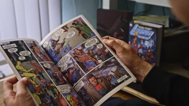 Через Плечо Крупным Планом Человек Читает Красочные Комиксы Переворачивает Страницы — стоковое видео