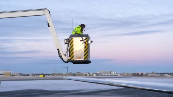 机场职员在冬季及黄昏期间在飞机机翼上使用除冰液 — 图库视频影像