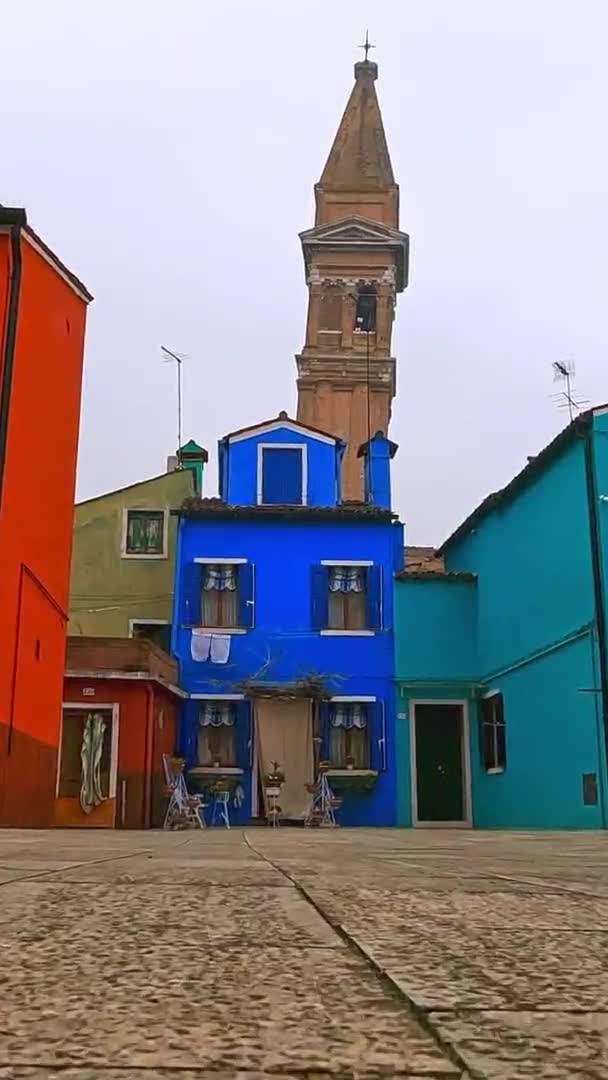 カラフルな家やイタリアのブラーノ島の傾いた鐘楼に向かって低角度の地上表面Fpv Pov スローモーション 光学式 — ストック動画