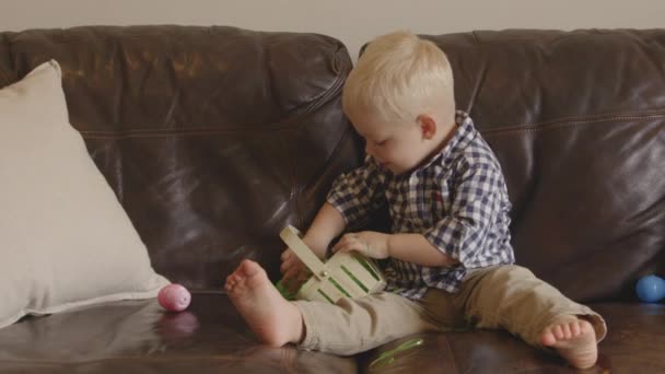 Slow Motion Shot Boy Sitting Sofa Playing Easter Eggs — стоковое видео