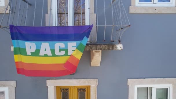 虹の旗の周りを飛ぶことはゲイプライドフラグとしても知られています碑文 イタリア語 平和はリスボンのバルコニーにかかって ポルトガル — ストック動画