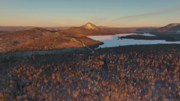 Wide Aerial Overlooking Frozen Lake Woodland Stretching Mountains — Vídeos de Stock