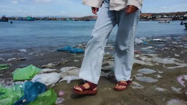 在被海洋塑料垃圾污染的肮脏海滩上散步的女孩 — 图库视频影像