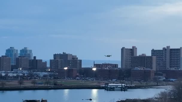 在一个多云的夜晚 在纽约布鲁克林的Calvert Vaux公园上空俯瞰空中风景 无人驾驶相机卡车离开了 又盘旋了一架无人驾驶飞机 周围是远处的公寓楼 — 图库视频影像