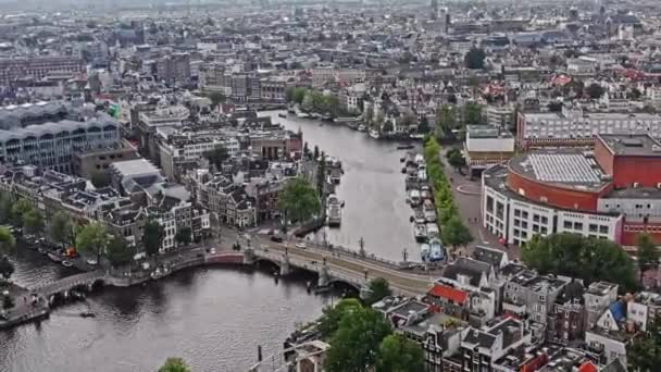 アムステルダムオランダ空中のV28鳥の目のビューパンは アムステルダムの水上運河と国立オペラとバレエ劇場でダウンタウンの街並みを見下ろすブルブルブルック橋の周りに撃たれました 8月2021 — ストック動画