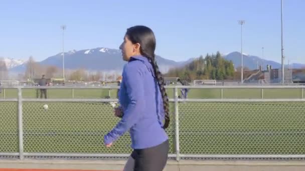 年轻的拉丁女子 辫子在跑道上奔跑 侧随射击 — 图库视频影像