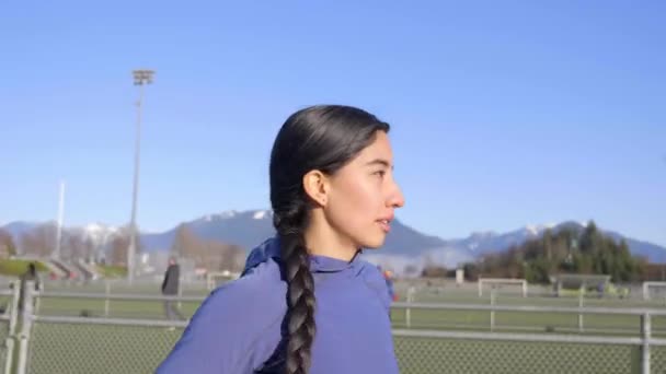 Closeup Young Hispanic Woman Jogging Race Track Follow Pan — Stockvideo