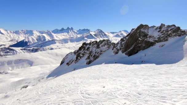 空中的积雪覆盖了山地景观 岩石形成和滑雪者的轨道在前景 阳光灿烂 — 图库视频影像