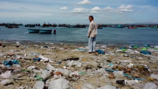 白人の女の子だけで汚れた汚染されたビーチに立ってプラスチックの海のゴミでいっぱい — ストック動画