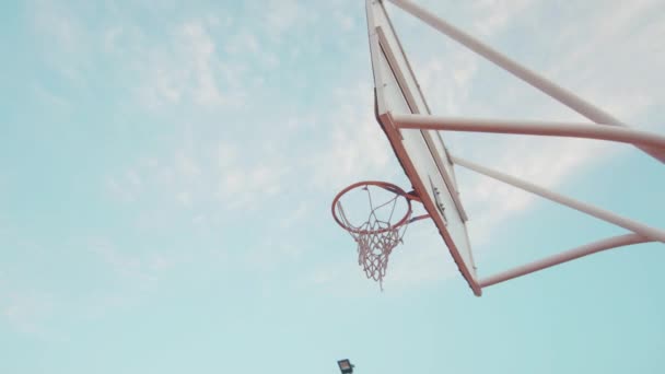 Basketball Fällt Freien Gegen Blauen Himmel Und Sonne Ins Korbnetz — Stockvideo