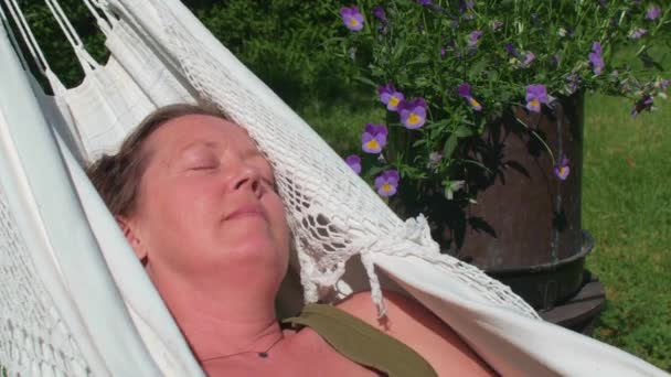 中年女性は顔に太陽とハンモックで静かにリラックスしました — ストック動画