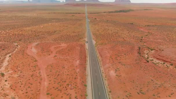 ドローンに続くシルバー車のアリゾナ州とユタ州のモニュメント バレーで有名な日当たりの良いアメリカ砂漠高速道路道路に沿って運転 — ストック動画