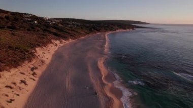 Aerial drone footage of people swimming at beach at sunset