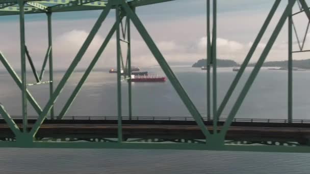 前景に金属製の橋を持つ川の4K航空コンテナ船右ショットに左ドローントラック — ストック動画