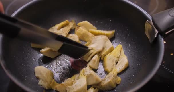酱汁朝鲜蓟 典型的西班牙菜 的特写是在一个煎锅里用油和调味品搅拌的 — 图库视频影像