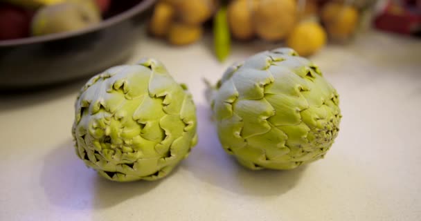 Close View Two Fresh Spanish Artichokes White Kitchen Counter Other — стоковое видео