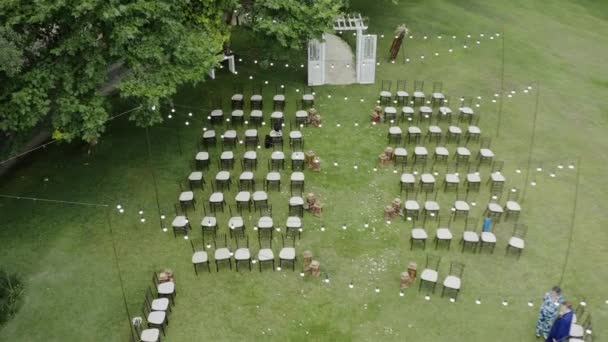 在树下的绿地上俯瞰着婚礼场地 在草坪上装饰装饰的婚礼传统 一排排喜庆的椅子和美丽的花朵在篮子里 图象4K — 图库视频影像