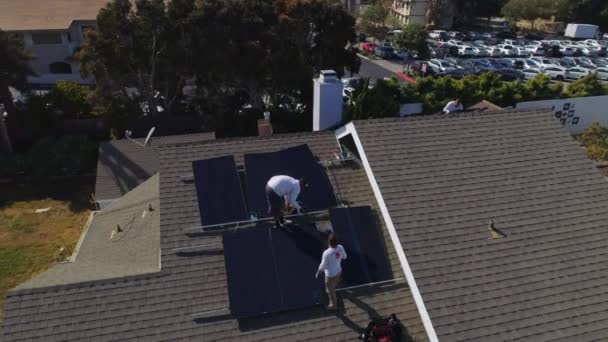 屋上の労働者の周りの航空軌道は 太陽電池パネルの設置とメンテナンスを実行していますロサンゼルス カリフォルニア州 ドローンショット — ストック動画