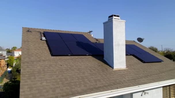カリフォルニア州ロサンゼルスの晴れた日にソーラーパネルが設置された近所の家の屋上の周りのドローン低軌道 ドローンショット — ストック動画