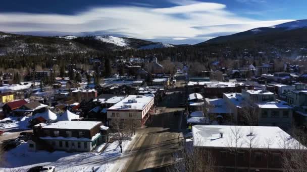 在科罗拉多州的主要道路上 空中飞驰而过 背景上覆盖着雪山 道路两旁的建筑物都在前方 — 图库视频影像