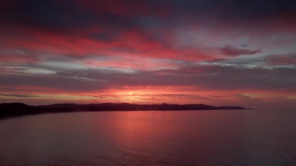 ニュージーランドの北の島 スピリットベイのマウンテンシルエットの雲の後ろの夕日 空中ワイドショット — ストック動画