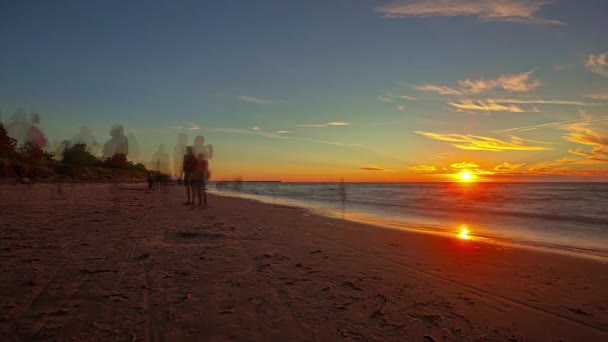 バルト海沿岸の休日の水平線で黄金の夕日を撮る観光客の散歩 — ストック動画