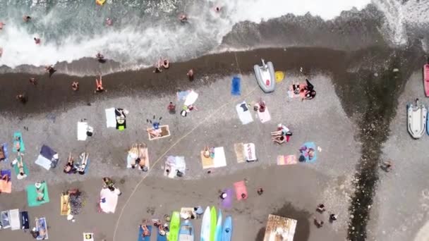 空中无人驾驶飞机旋转拍摄沙滩与一排五彩斑斓的雨伞 游泳的人在海湾与透明蓝色的水在夏天 意大利阿马尔菲海岸 — 图库视频影像