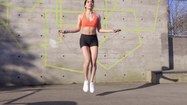 年轻拉丁女人用钢丝绳跳混凝土墙 宽射门 — 图库视频影像