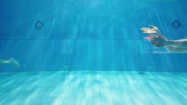 Underwater of beautiful sexy young blonde woman in red one-piece swimsuit and goggles, swimming alone and greeting in apnea holding the breath