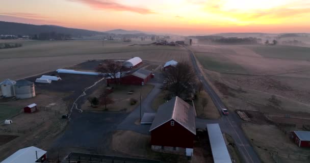 美国农村农场的建筑物在早晨冬日的日出 汽车在路上驶过谷仓 — 图库视频影像