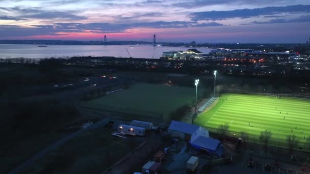 An aerial time-lapse during a spectacular sunset in Brooklyn, New York. An illuminated green soccer field is a beautiful contrast to the colorful sky and clouds moving up above.