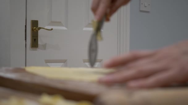 パン屋さんの手のフォーカスショットをラッキングピザカッターでFaworki生地を切断 背景に白い木製のドア 閉めて — ストック動画
