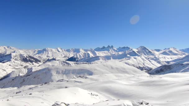 空中拍摄高空飞越冬季运动场地 宽阔的 远眺雪山和远处的一些小滑雪者 阳光灿烂的日子 — 图库视频影像