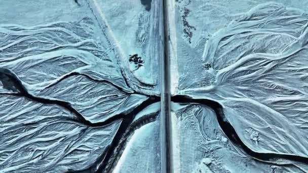 冰岛南部冬季 一架独行汽车在冰封的冰河上过桥时 头顶上的无人驾驶飞机射击 — 图库视频影像