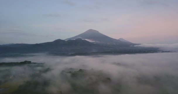 晴れた日と曇りの日の間に霧で覆われた熱帯の風景の上の神秘的な空中前方飛行 バックグラウンドで大規模なサミング火山 — ストック動画