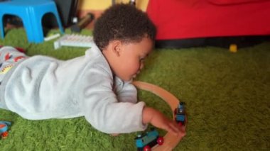 İki yaşındaki egzotik ve sevimli Afrikalı çocuk oyuncak treniyle evde oynuyor.