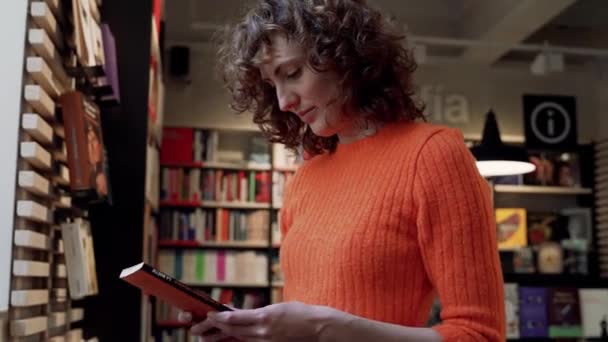 Educado Slim Rizado Mujer Hojeando Libros Tienda Multimedia Europea — Vídeo de stock