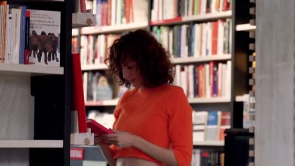 Curly Leitor Feminino Caucasiano Navegando Para Livros Livraria Corredor — Vídeo de Stock